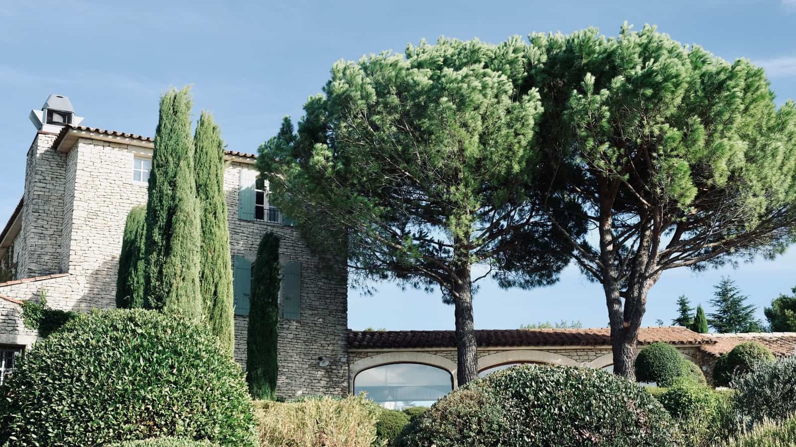 Bastide provençale en pierre entourée de cyprès et de pins parasols