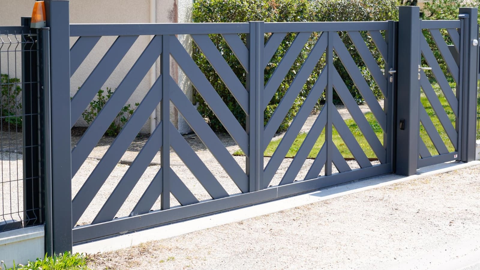 Portail en aluminium anthracite à lames croisées avec son feu clignotant de motorisation