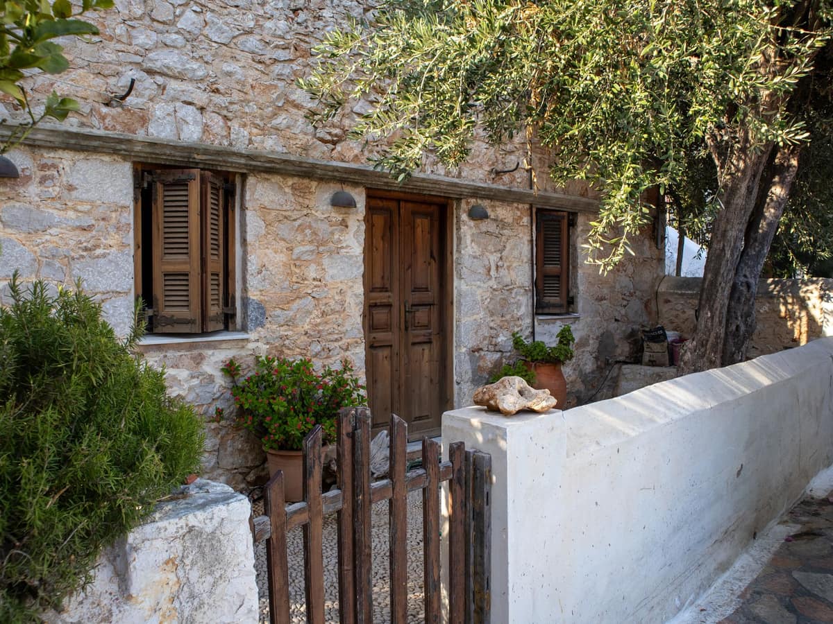 Entrée d'une maison en pierre avec portillon en bois et olivier